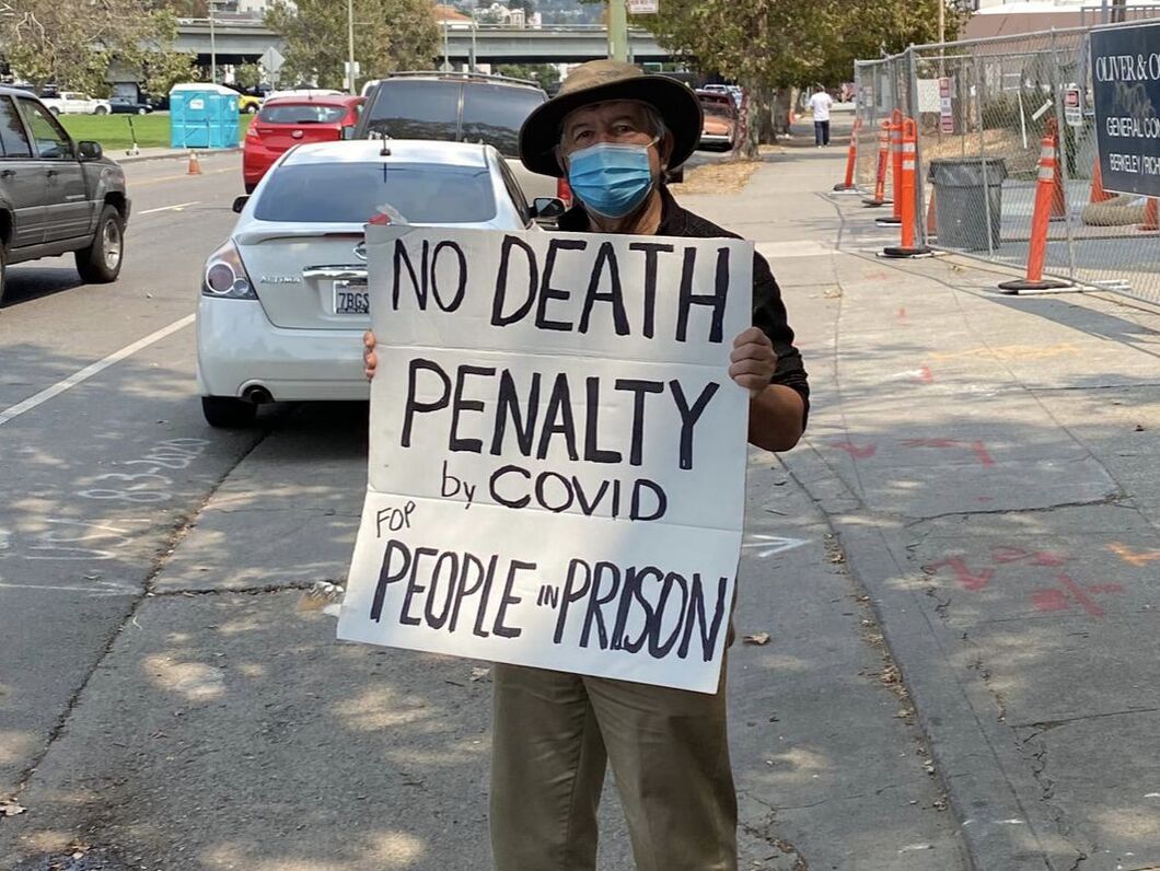  A person holding a protest sign that says No Death Penalty by Covid for People in Prison