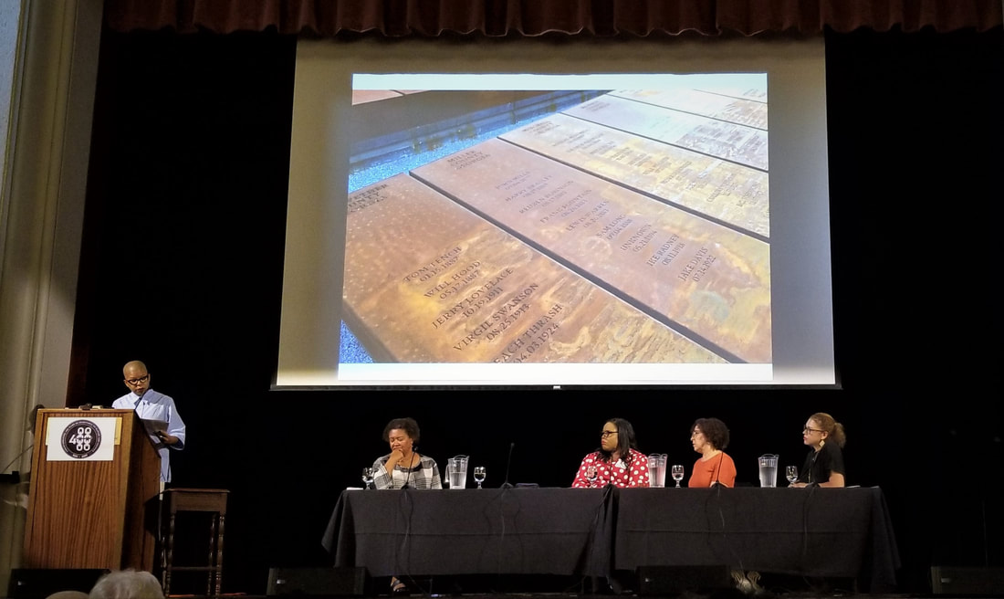 The panel on ‘Slavery, Memory, Afterlife’ with C. Sharpe speaking at the podium and seated (left to right) L. Harris, S. Jones-Rogers, G. Foreman and T. Sacks (moderator), beneath a slide of the steel columns on the ground at the National Memorial for Peace and Justice. (Photo by M. Luckey)Picture