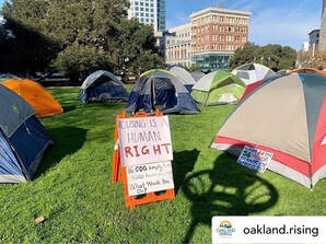 Image of tents and a sign that reads “housing is a human right.”